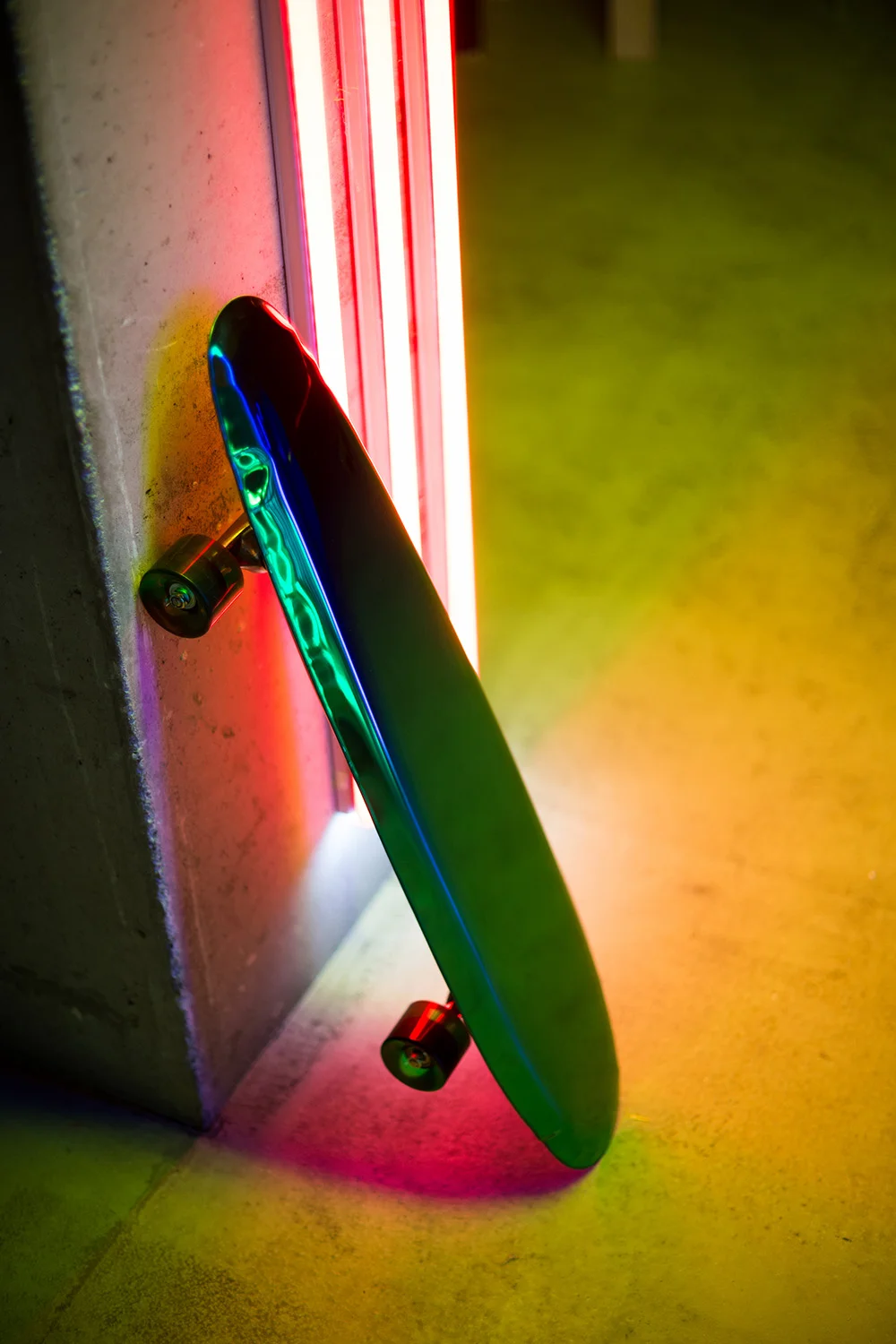 COLORFUL NEON LIGHTS REFLECTIONS IN BOLID OBJECT PROPPED UP THE WALL